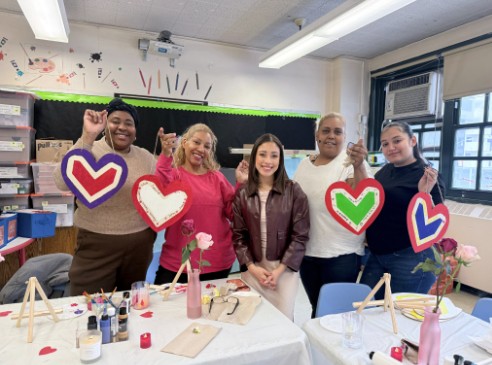 Five people holding painted heart decorations at school Valentine event