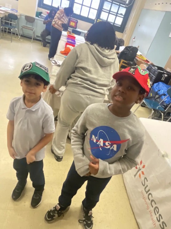 Two students wearing hats at a school event indoors