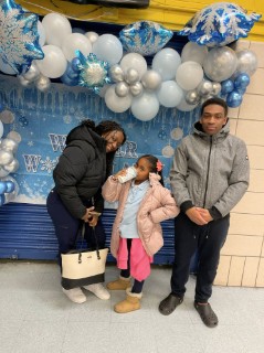 Family posing at school winter celebration with balloon decorations