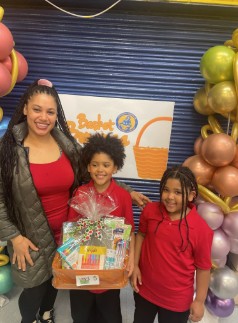 Student and family proudly holding a gift basket at school event