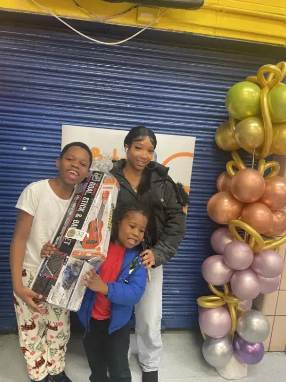 Students and adult posing with gifts at school holiday event