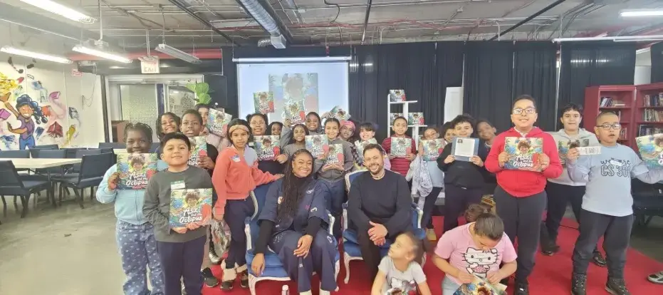 Students and adults holding copies of a book at a school event