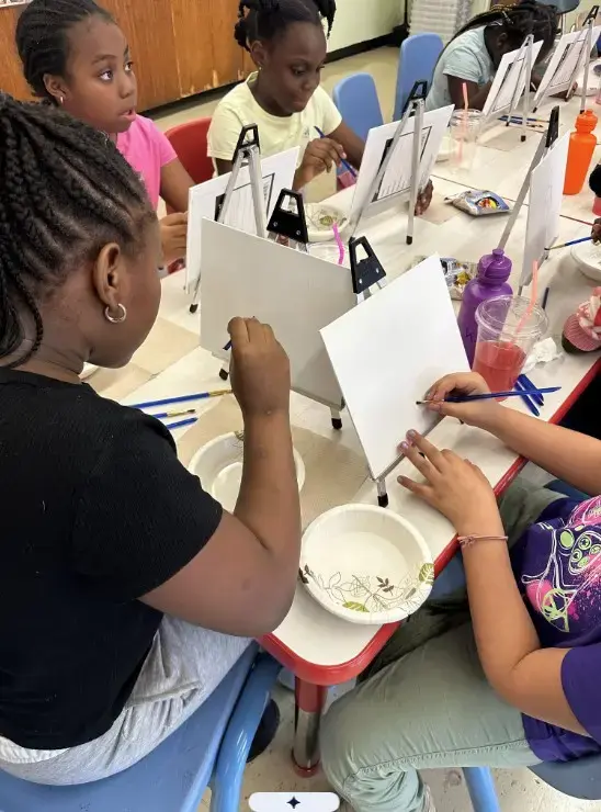 Students painting on canvases during a classroom art activity