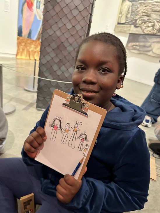 Student holding clipboard with hand-drawn family figures at museum