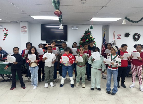 Students singing carols at a holiday performance holding sheet music