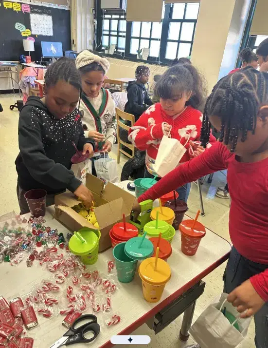 Students assembling holiday gift bags with candy canes in classroom