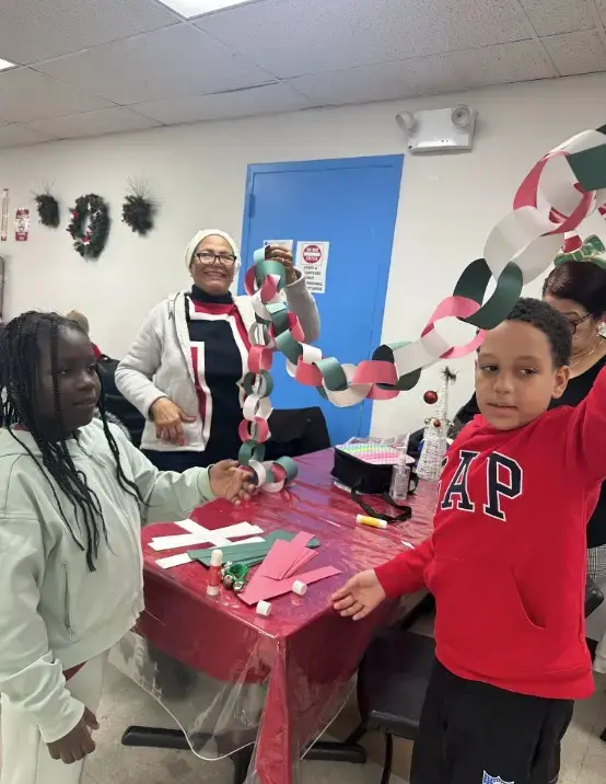 Students and adult displaying handmade red and green paper chain garland
