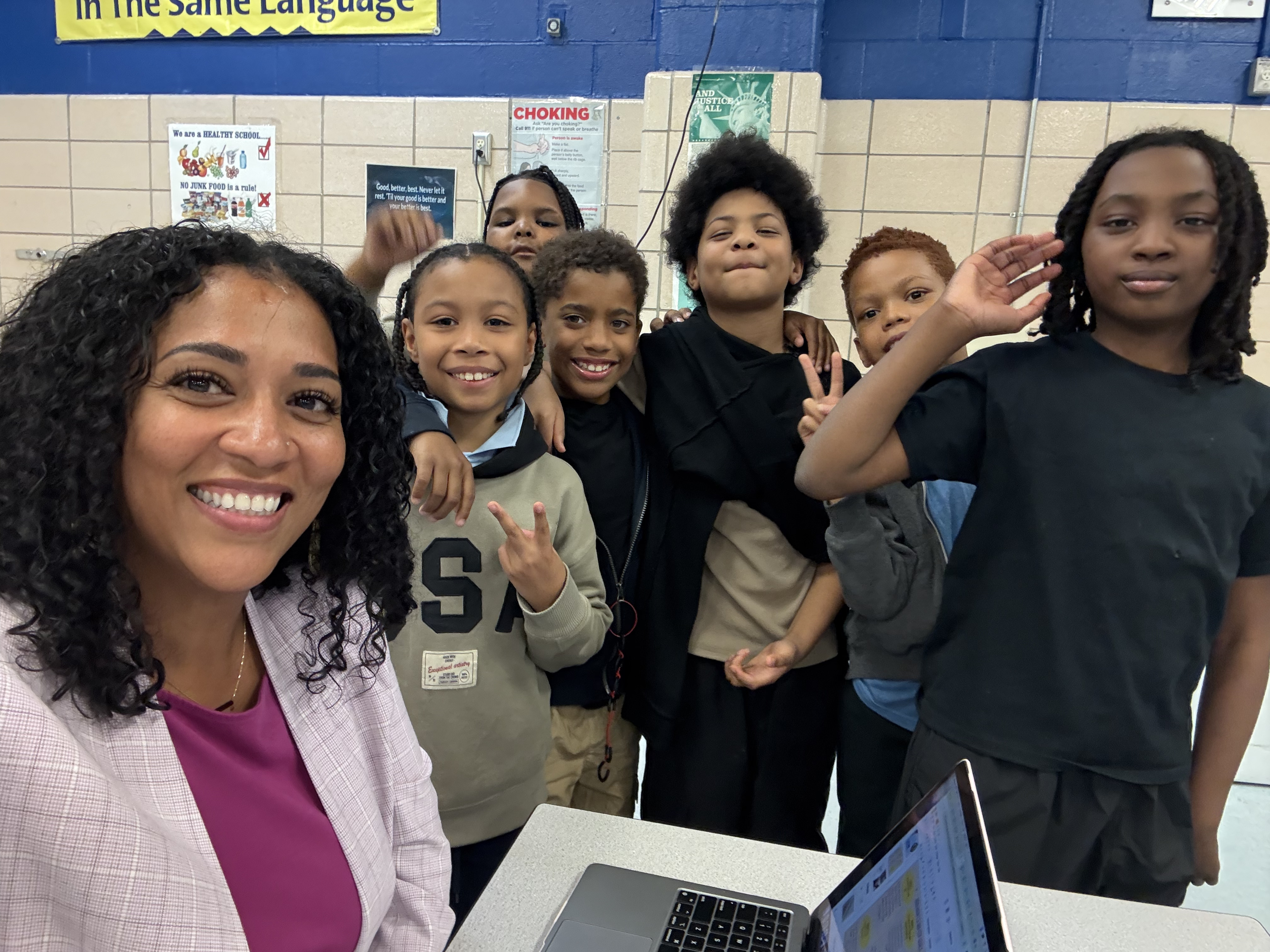 Teacher smiling with six elementary students in school cafeteria