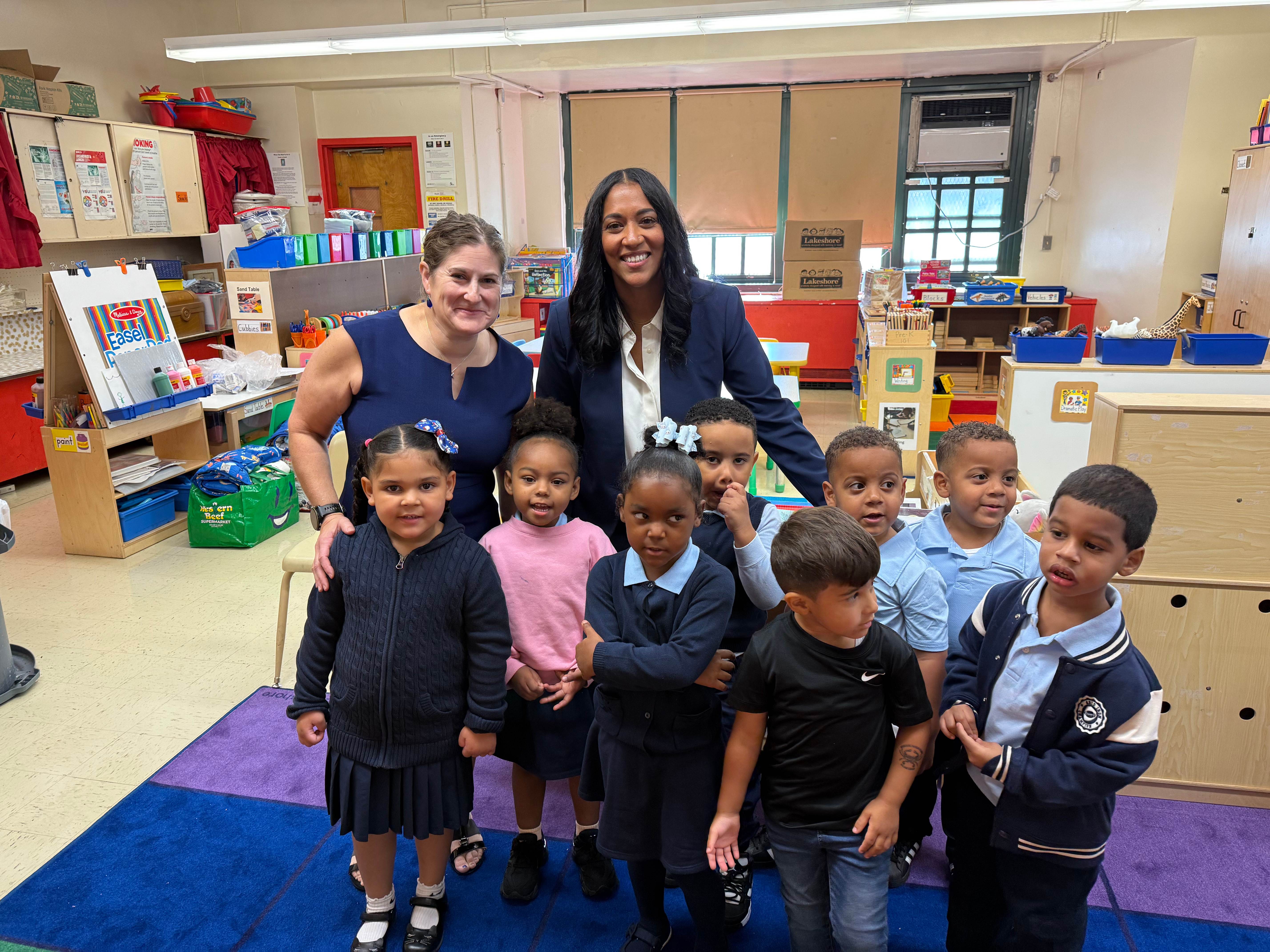 Two adults pose with a group of young students in a classroom