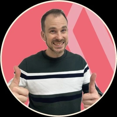 Photo d'Emmanuel Rösler avec un pull gris à rayures bleues et blanches, levant les pouces de chaque main