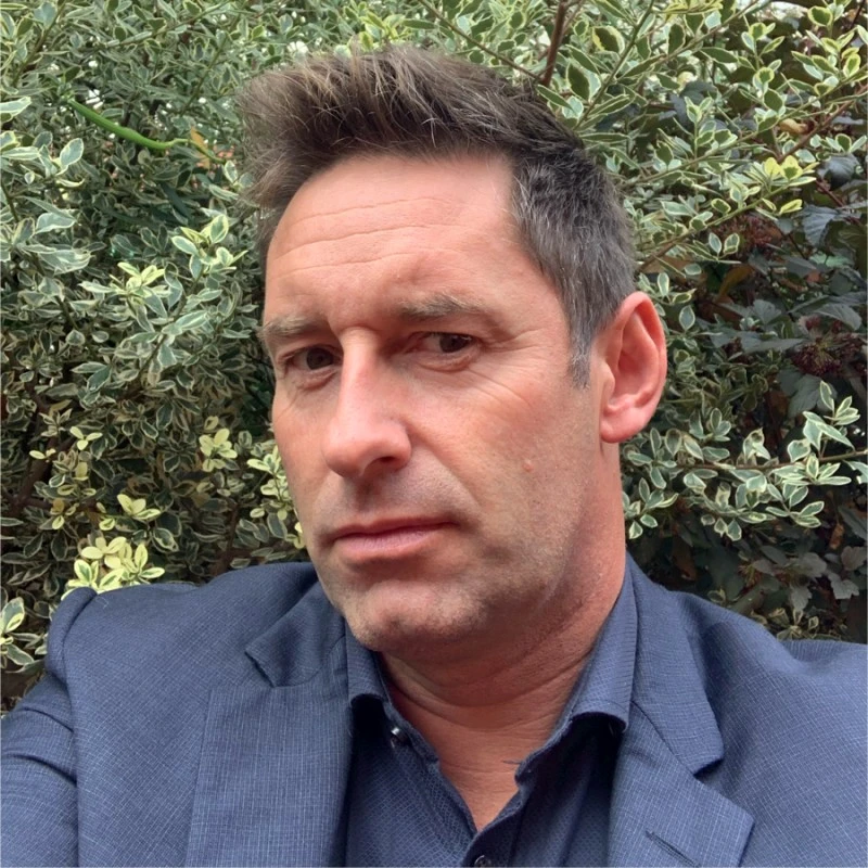 Cyril Durand de face, cheveux bruns et portant une chemise et une veste bleu marine.
