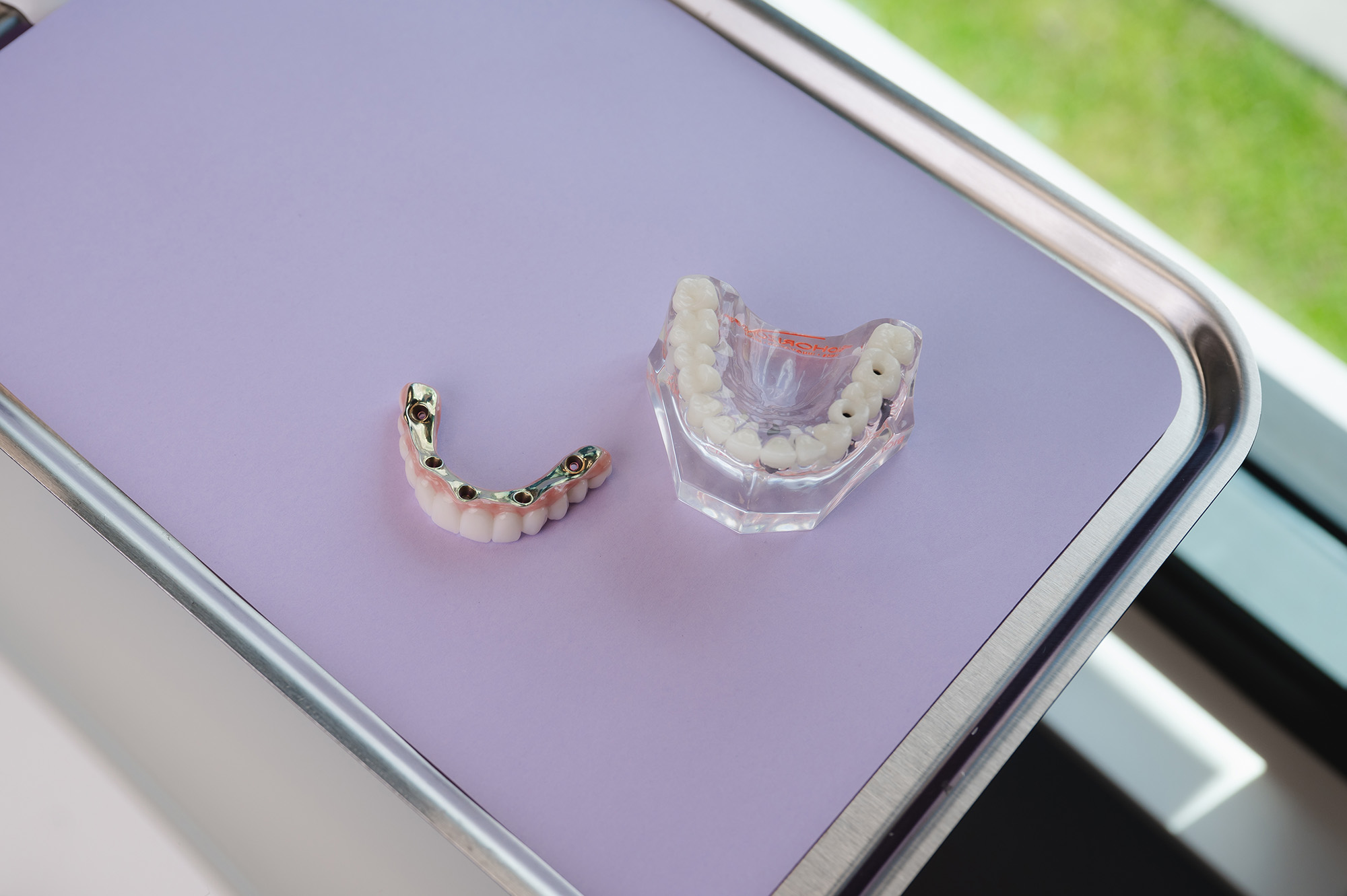 Modern dental chair in a bright clinic room with large windows showing greenery outside.
