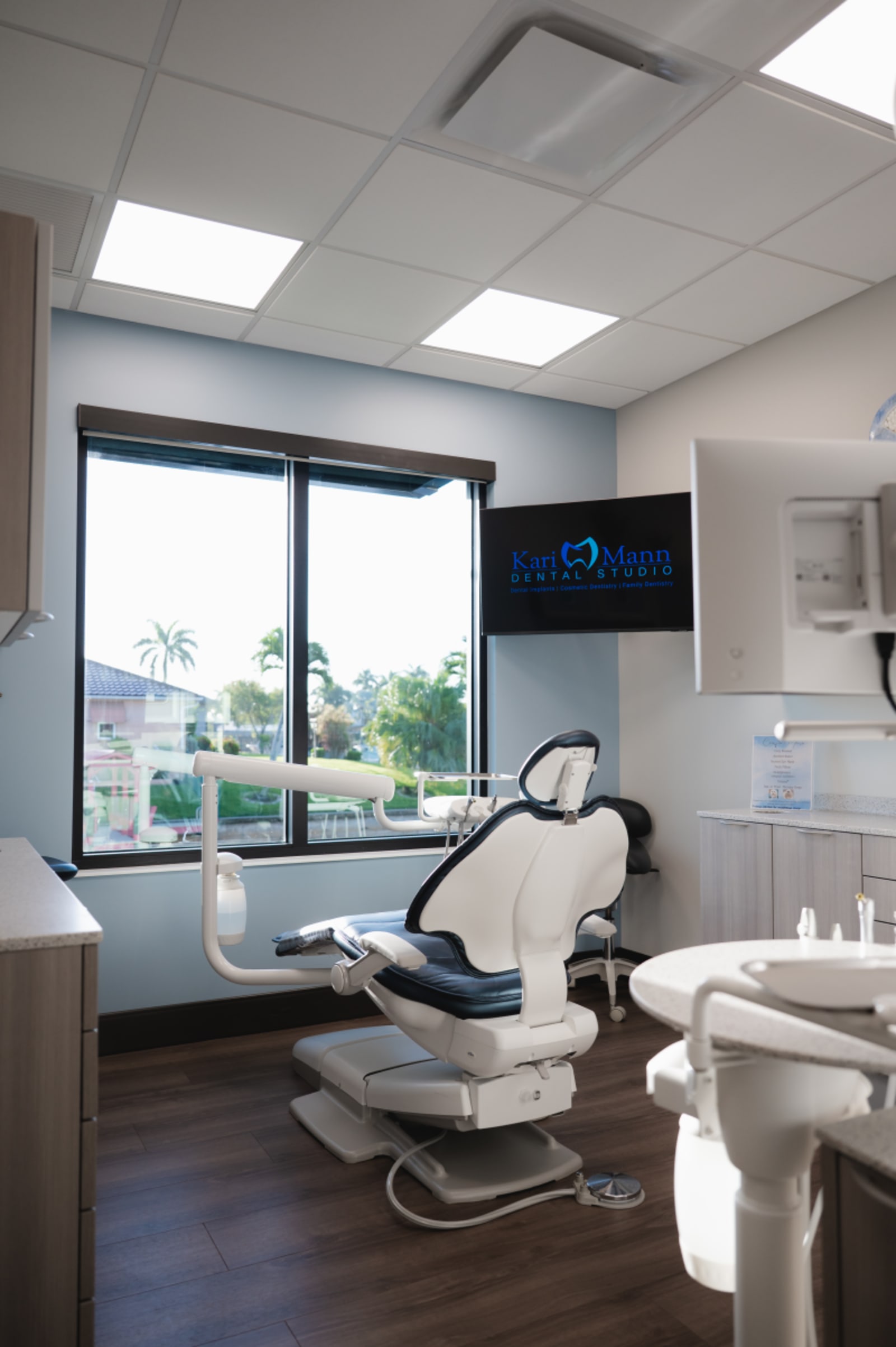 Modern dental treatment room with chair, equipment, and waterfront windows