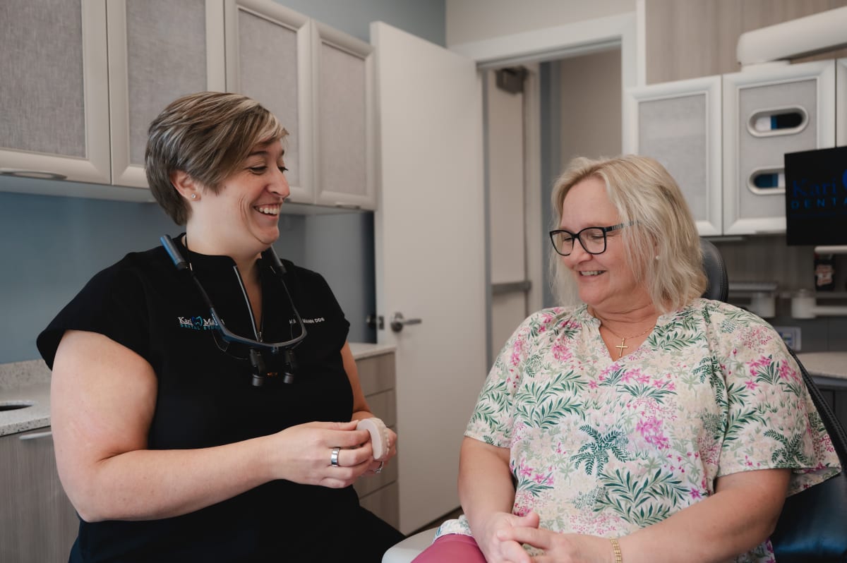 Dentist in black shirt consulting with female patient about treatment options in clinical setting