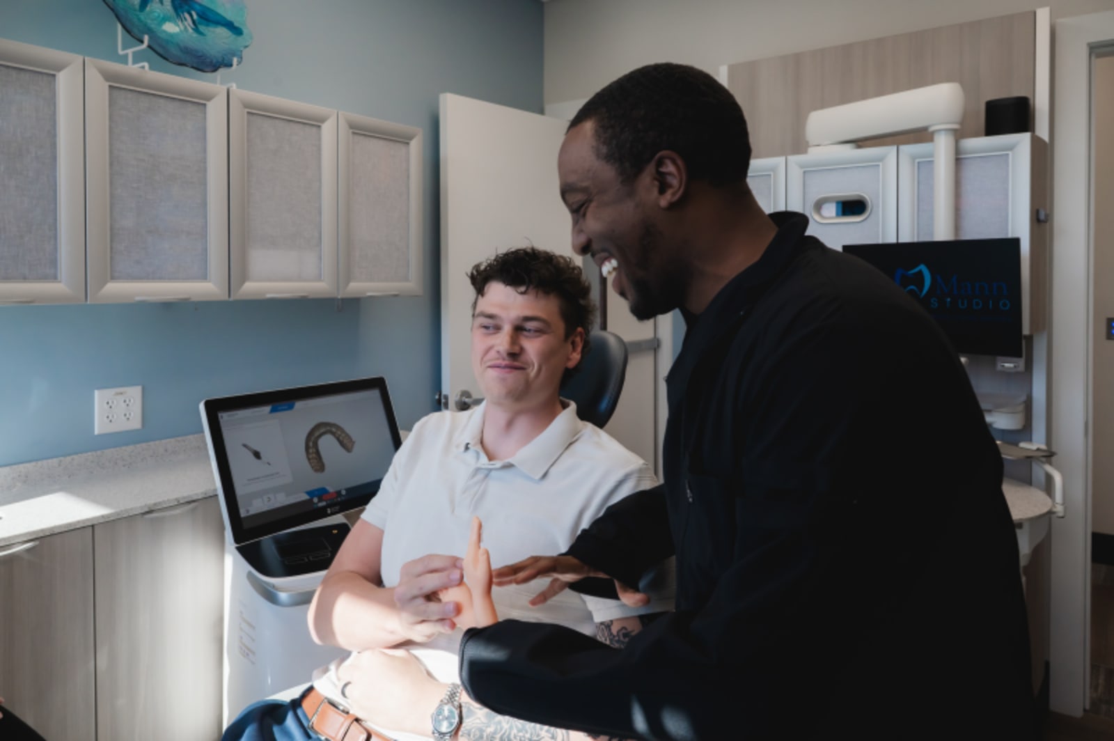 Dentist and male patient reviewing treatment plan on laptop computer together