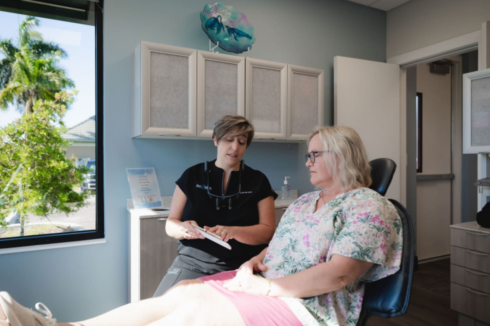 Dental professional consulting with patient in treatment room, discussing candidacy assessment