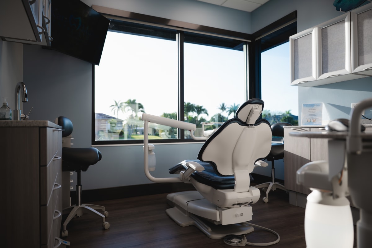 Modern dental operatory with treatment chair and equipment near large windows at Kari Mann Dental Studio.
