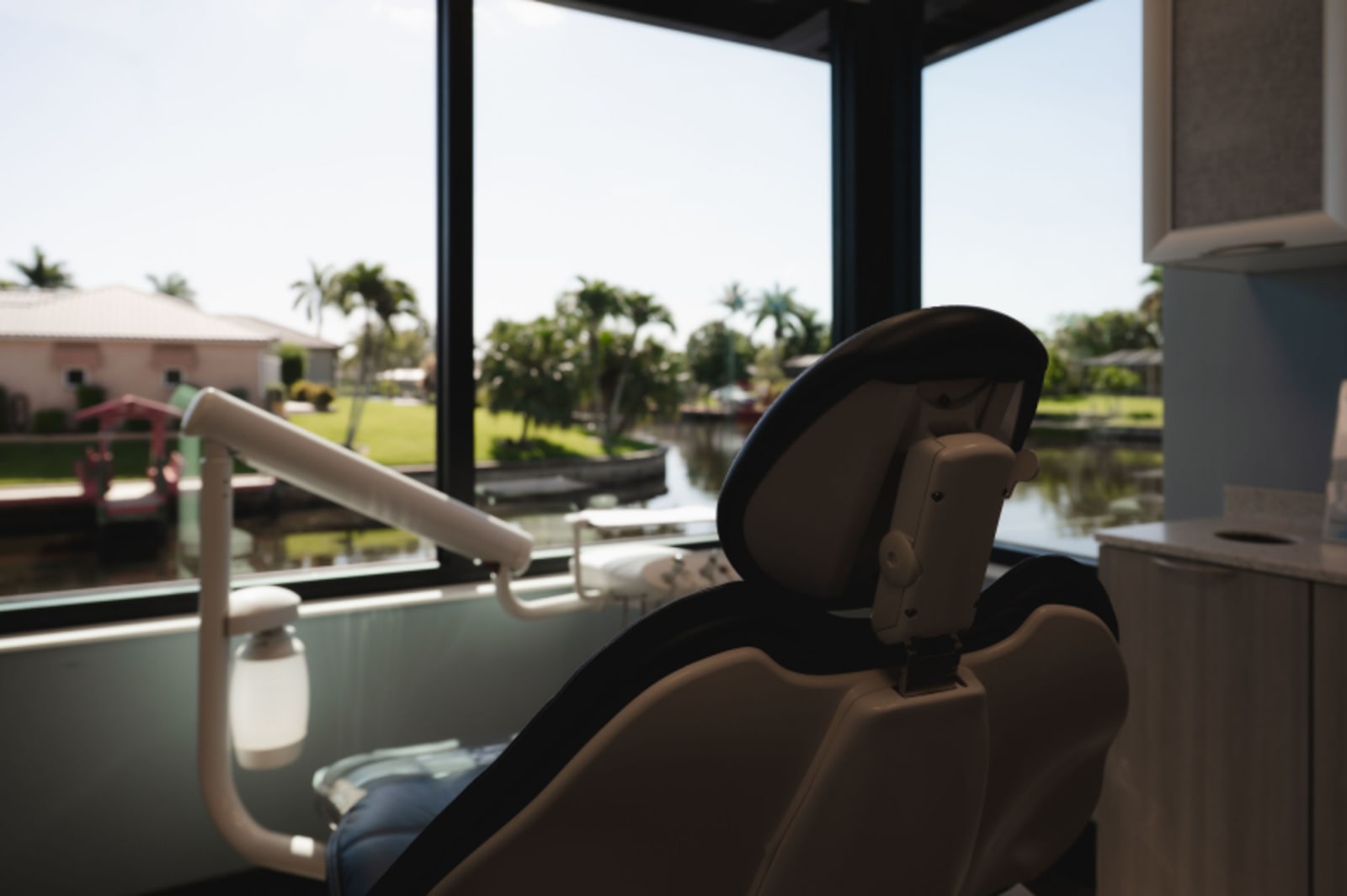 Patient relaxing in modern dental treatment chair with natural light and outdoor view.