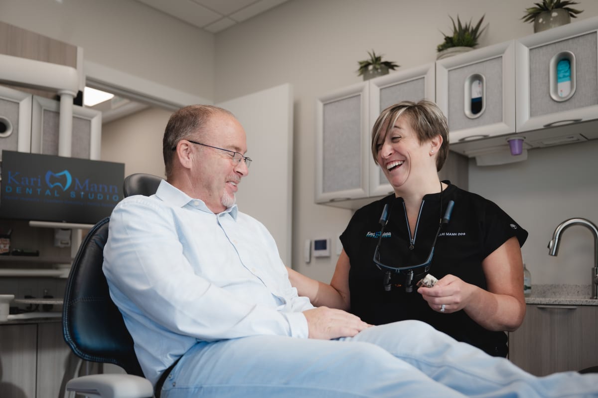 Dentist consulting with male patient in treatment room during dental examination