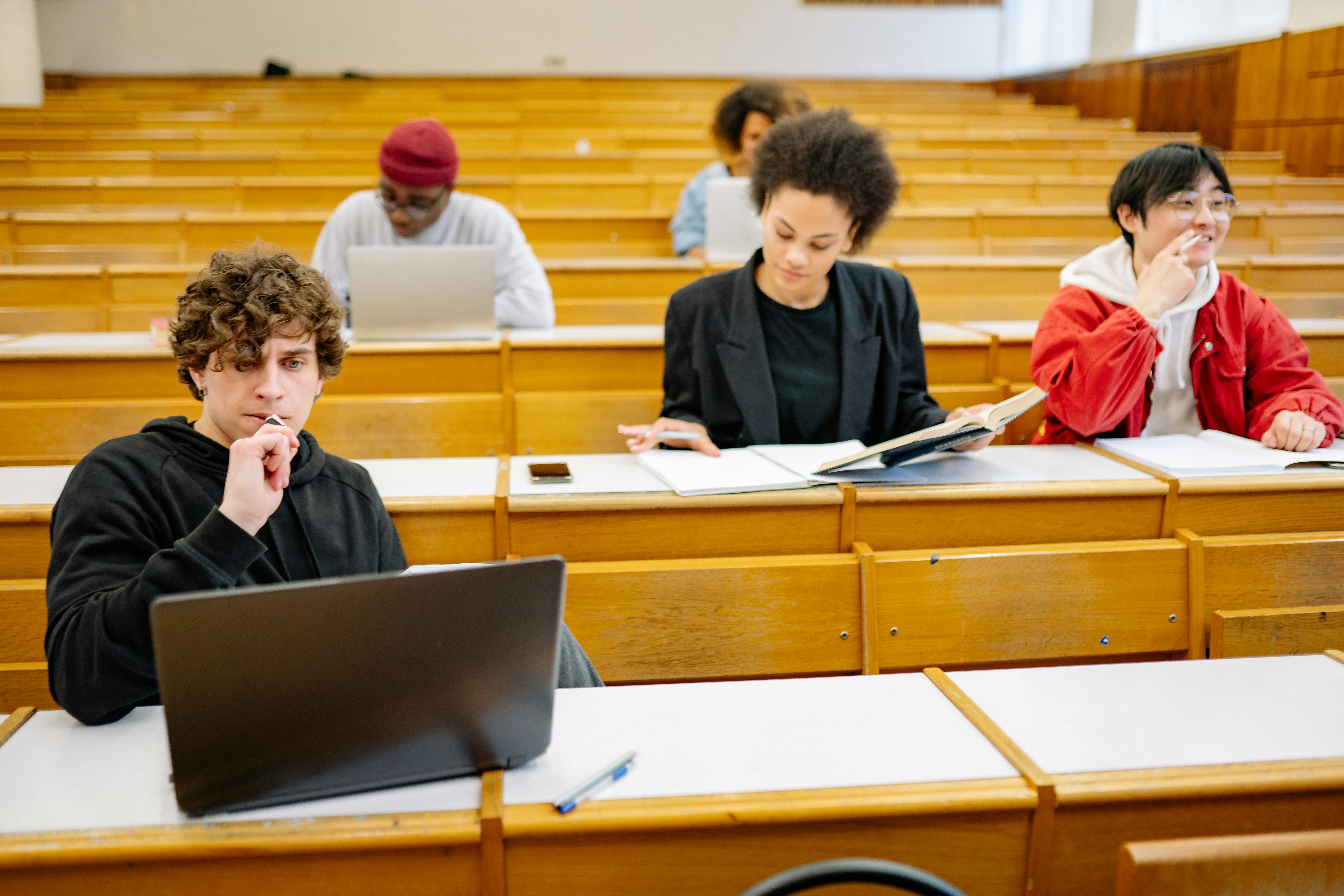 Several students sititng in a university classroom, each engaged in theri schoolwork.