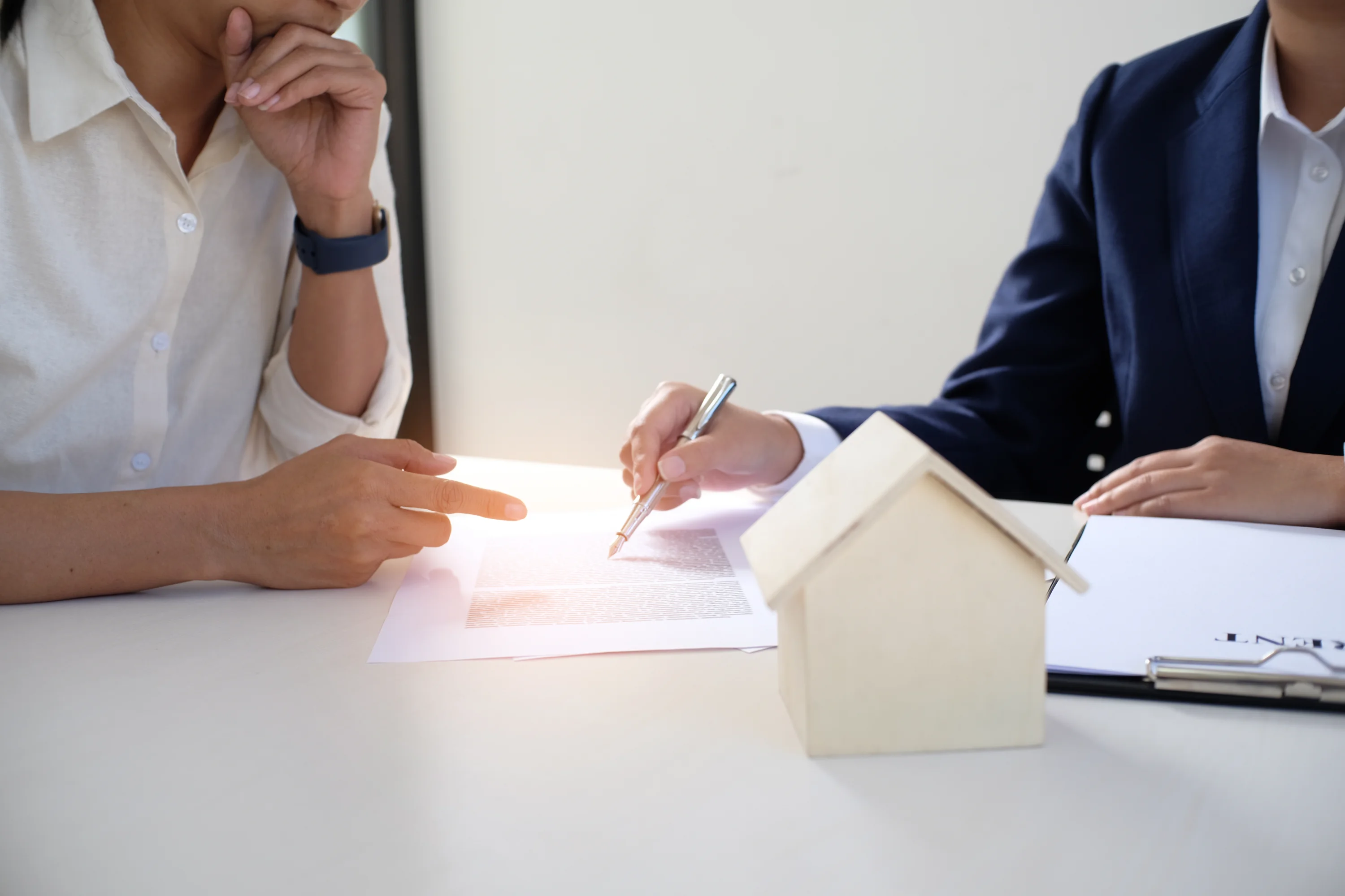 Two people sit at a table reviewing a document, one points while the other writes.
