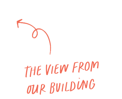 Curved arrow pointing left with the handwritten text below saying The view from our building in orange.