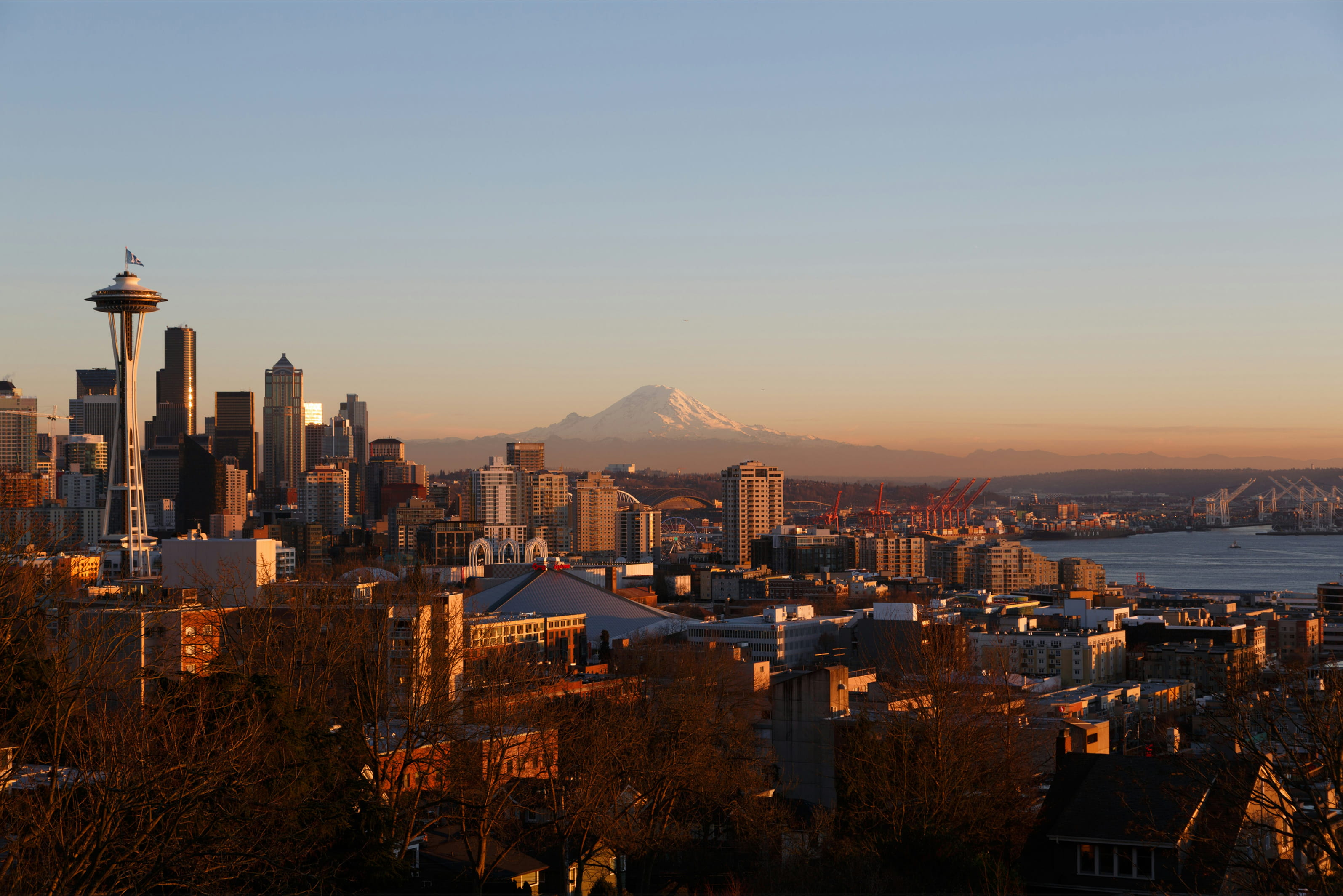 Seattle skyline at sunset with the Space Needle on the left and Mount Rainier in the background.
