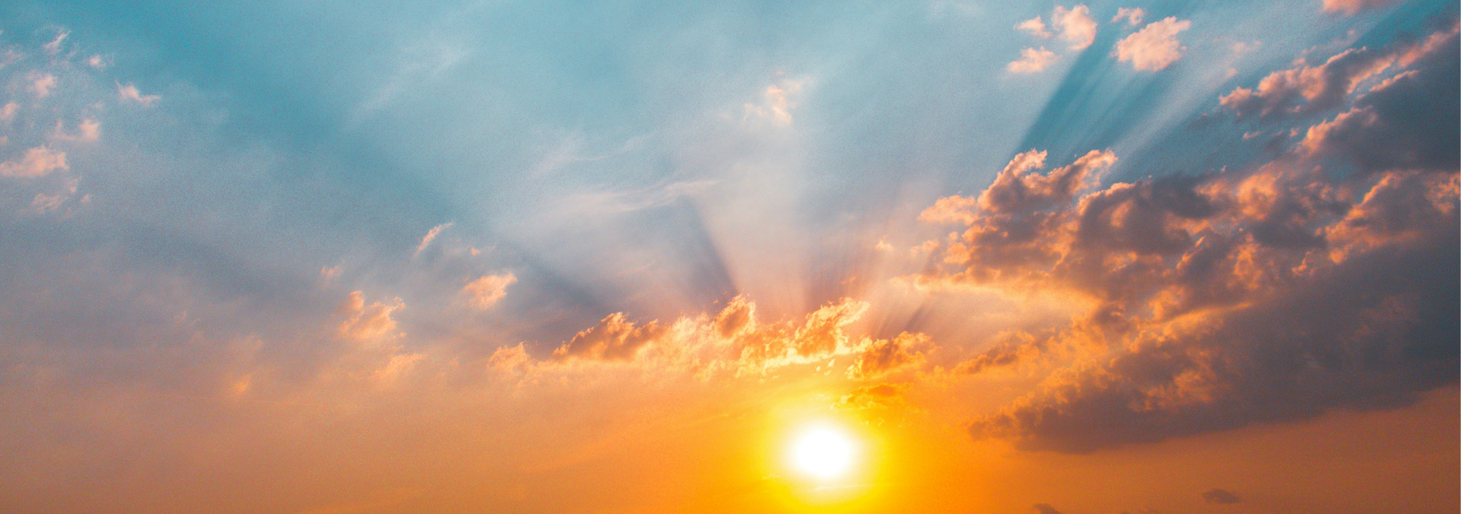 Sunrise Accounting & Bookkeeping | Sunset with sun partially obscured by orange and gray clouds with sun rays shining through blue sky.