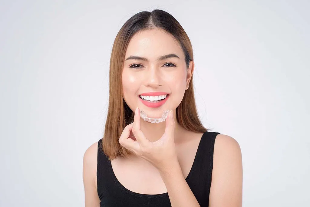 Young woman holding an Invisalign aligner