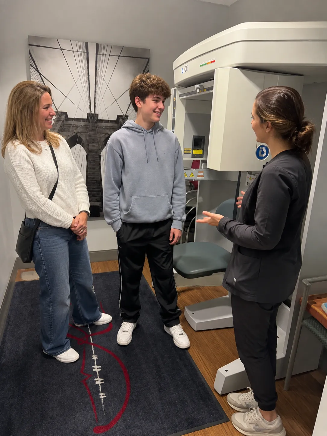 Mother and son with an orthodontic assistant near a CBCT scan machine