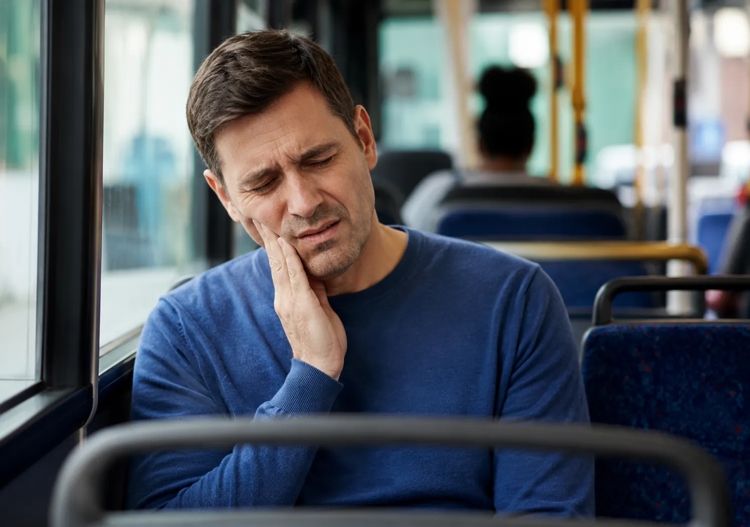 Adult man holding his jaw with TMJ-related discomfort. 