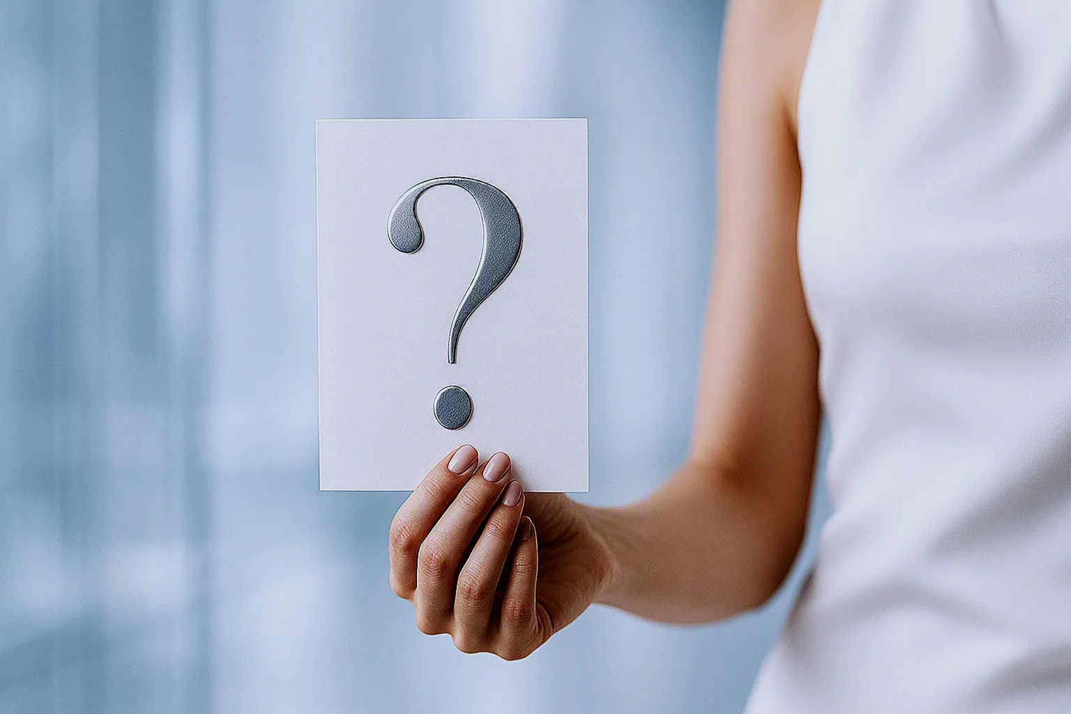 Hand holding a question mark card representing orthodontic FAQ information