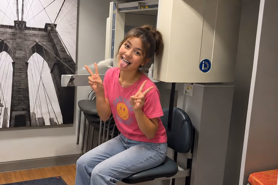 Happy teen with braces making peace signs at a 3D dental scanner