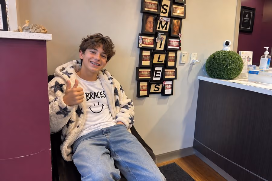 miling teen boy with braces giving a thumbs up