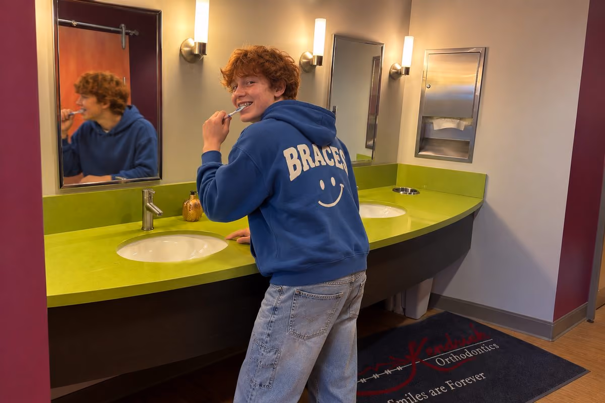 Teen with braces brushing his teeth at an orthodontic office brushing station