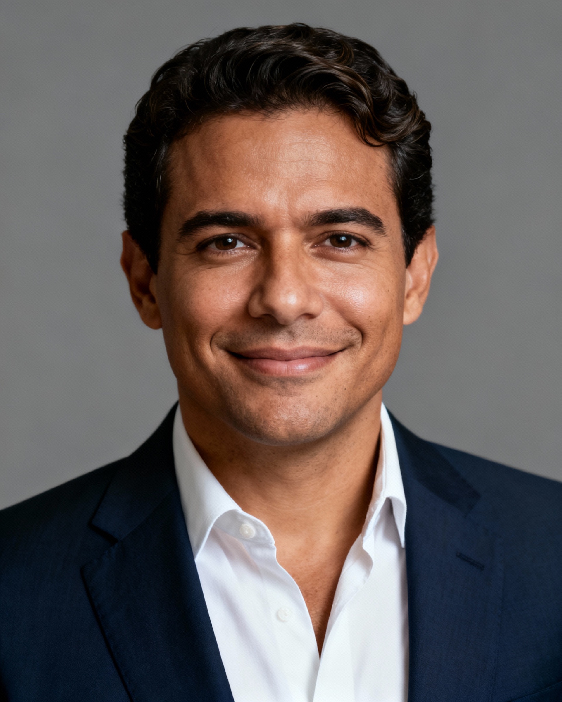Portrait of a Woodalls team member in a navy blazer and white shirt against a grey backdrop