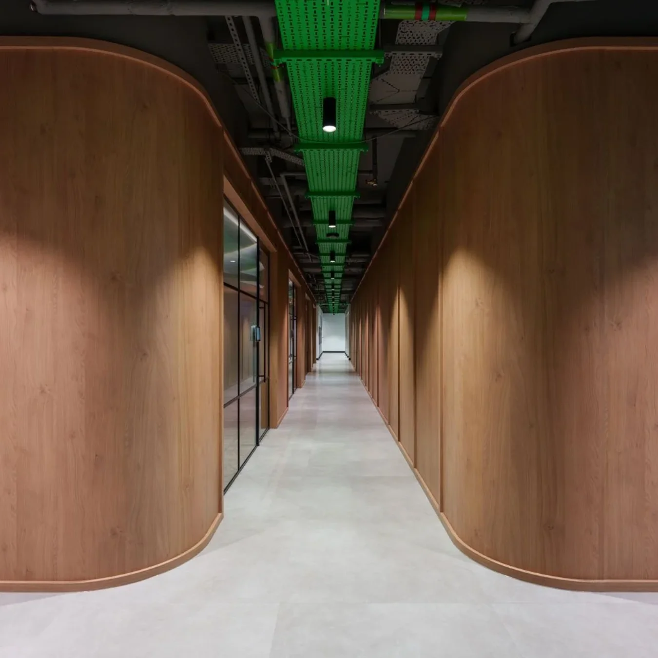 Curved timber-panelled corridor with green ceiling services at Schneider Electric