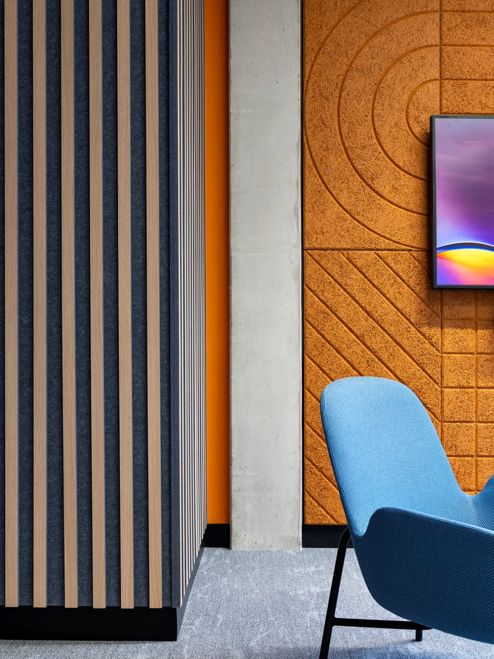 Blue lounge chair beside an orange feature wall with a concentric carved pattern at TomTom