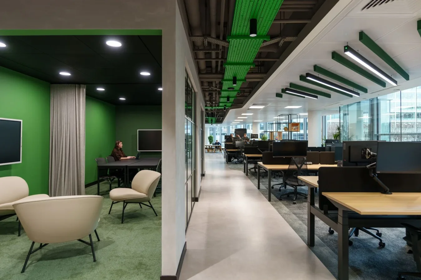 Open-plan office with a green breakout area and rows of desks at Schneider Electric