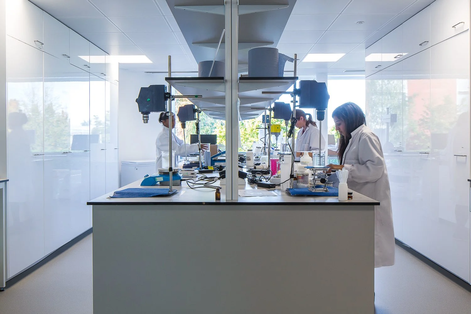 Scientist in a white coat working at a bench in a bright modern laboratory