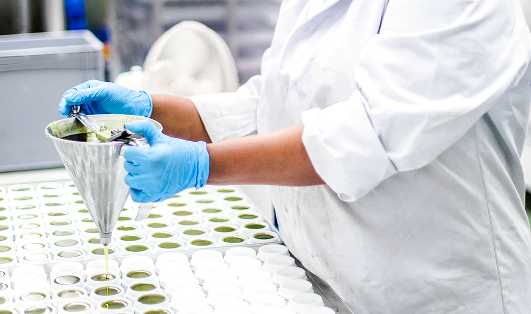 Lab technician in gloves pipetting a sample over a tray of vials