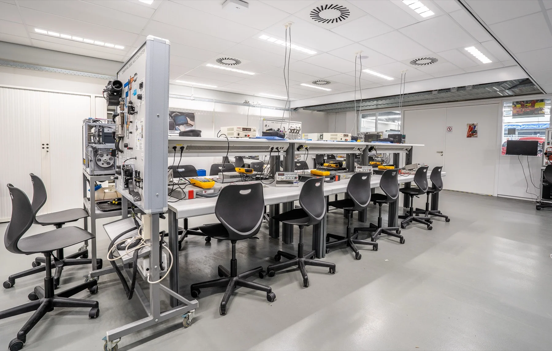 Laboratory with rows of benches, lab chairs and scientific equipment under bright lighting