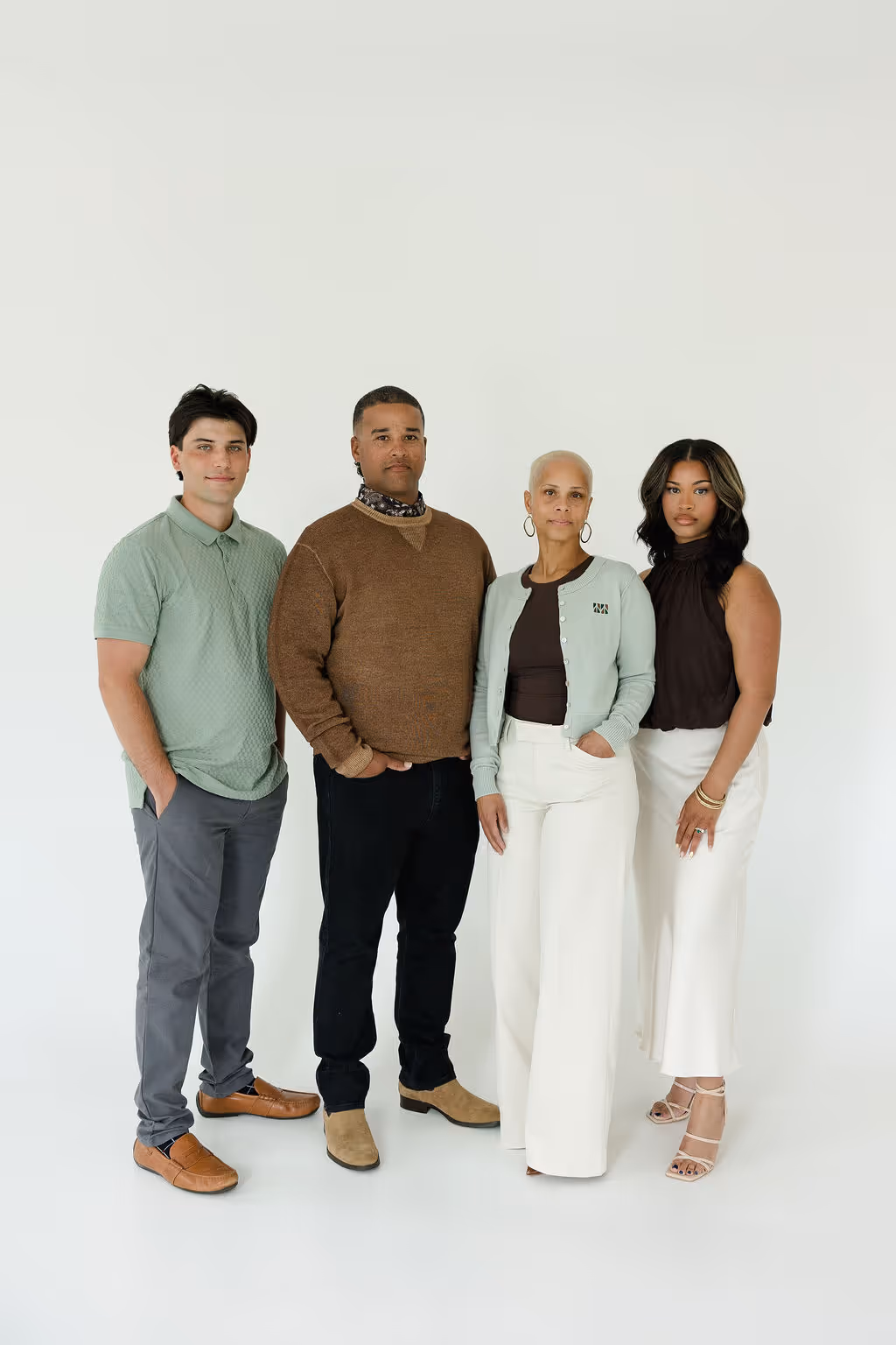 Four diverse adults standing in a row against a white background, dressed in casual and semi-formal attire.