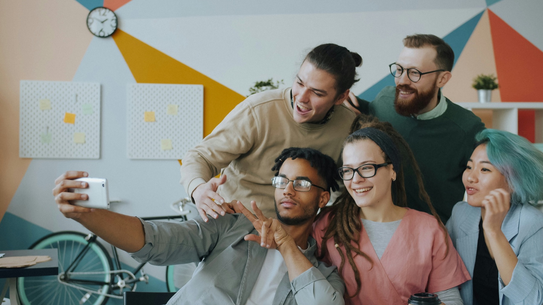 A team of colleagues taking a group selfie in a bright office