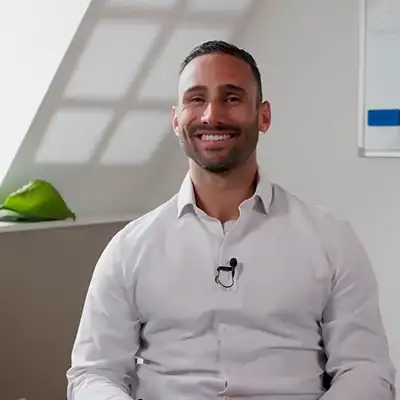 Yves Bill in weissem Hemd sitzt lächelnd bei einer Beratung.