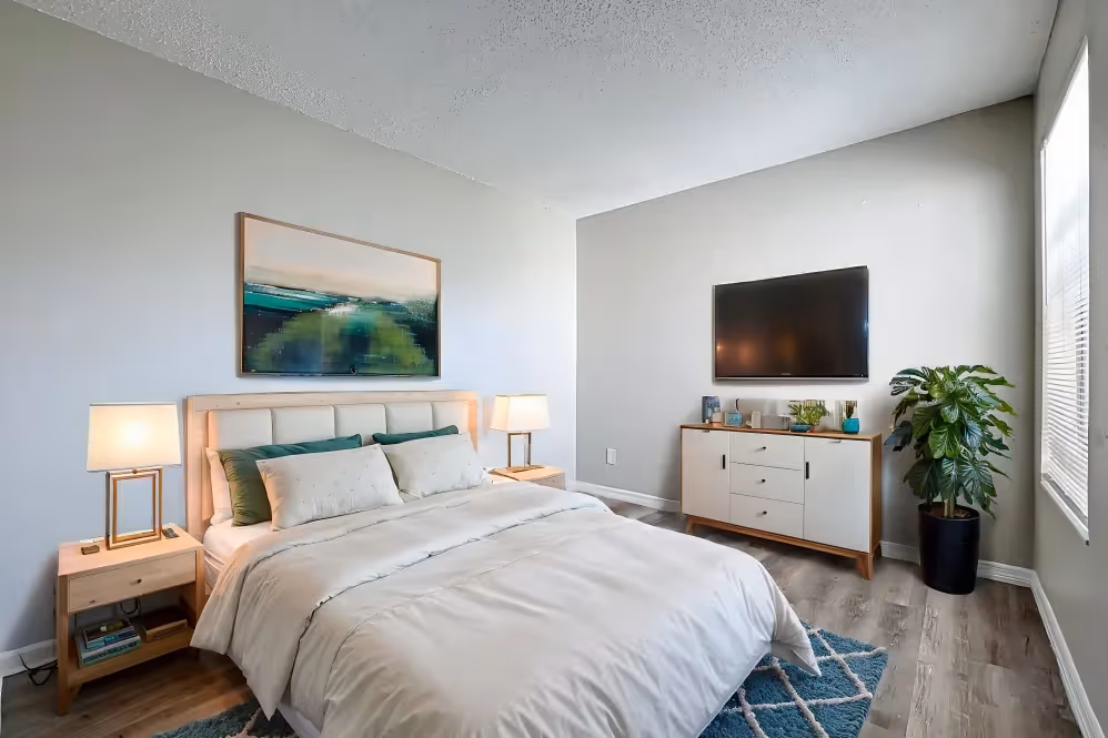 Bedroom with virtually staged furniture including bed, bedside table, tv, and dresser