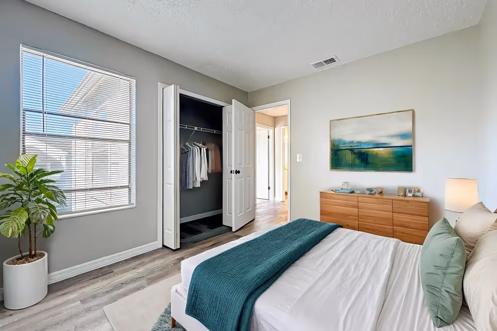 Bedroom with virtually staged furniture including bed, plant, and bedside table with lamp