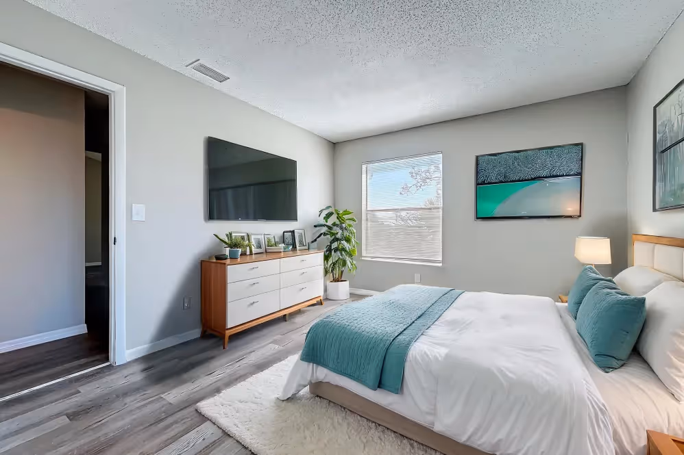 Bedroom with virtually staged furniture including bed, bedside table, tv, and dresser
