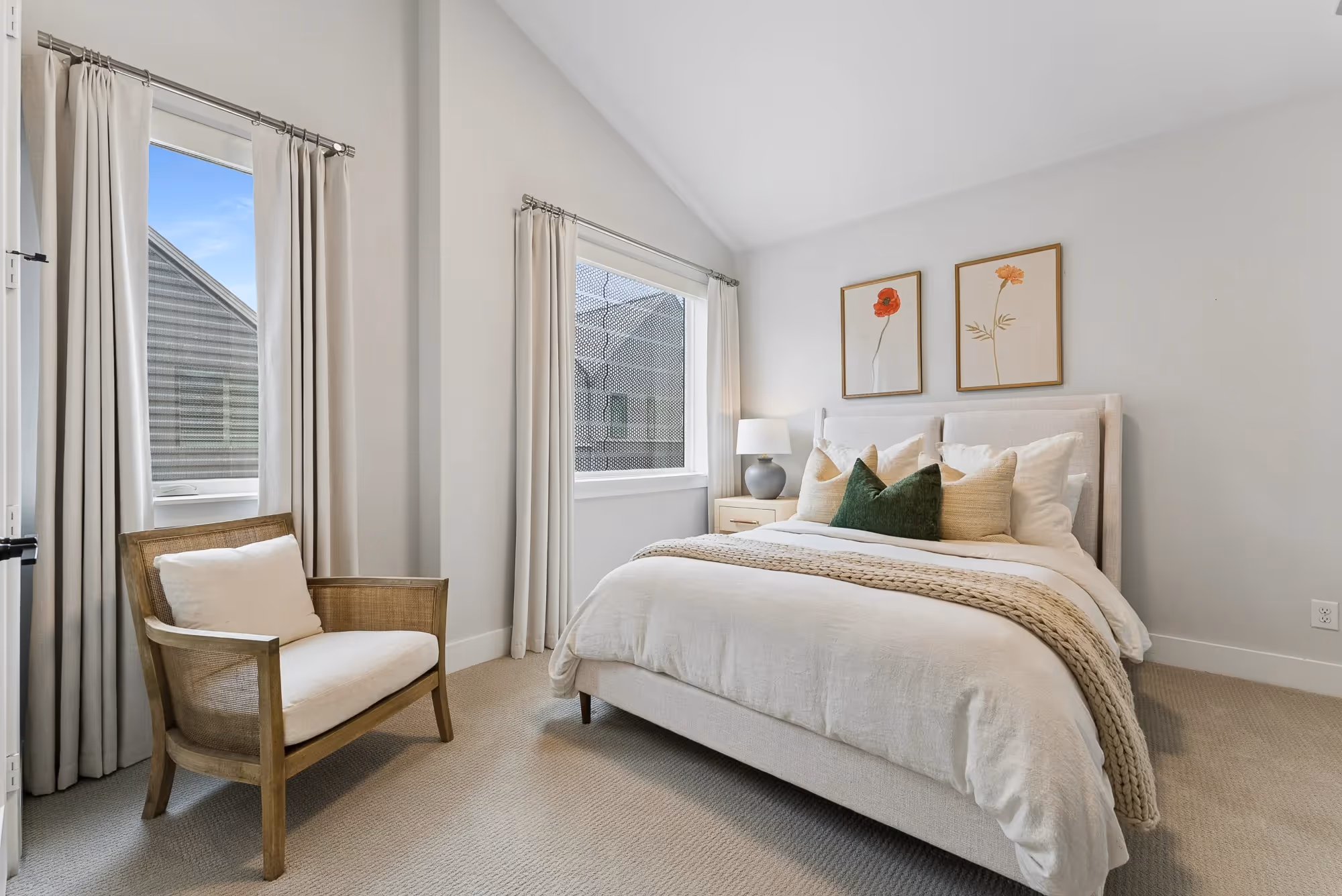Bright bedroom with upholstered bed, armchair, and large windows