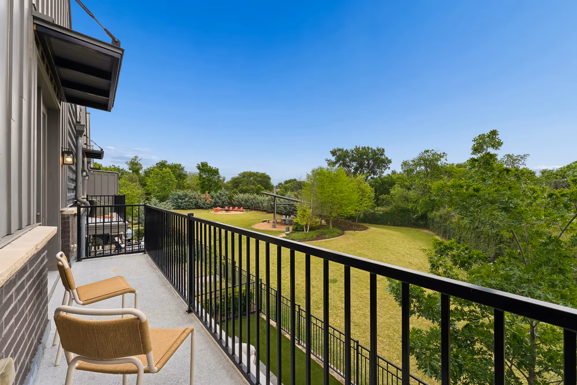 Balcony with black railing overlooking green landscape